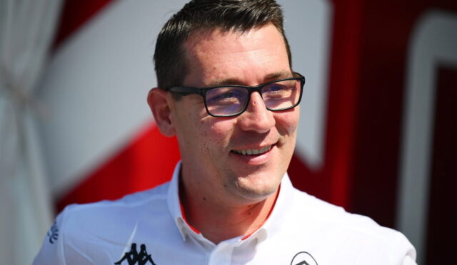 Portrait of a smiling man wearing glasses and a white polo with logos