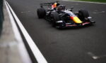Red Bull Racing Formula 1 car on a track near the barrier, black livery with a yellow nose.