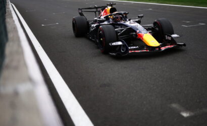 Red Bull Racing Formula 1 car on a track near the barrier, black livery with a yellow nose.