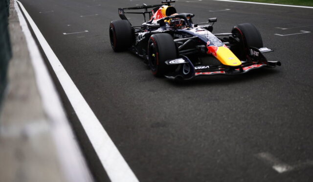 Red Bull Racing Formula 1 car on a track near the barrier, black livery with a yellow nose.