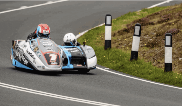 Sidecar motorcycle race rounding a bend on a paved road with white lane markings.
