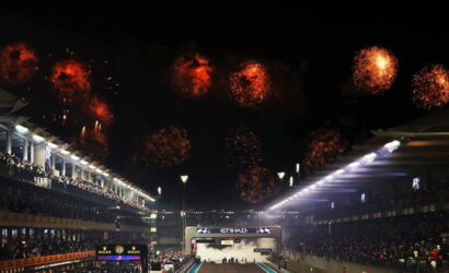 Nighttime motorsport finish with fireworks above a crowded grandstand and a lit finish line.