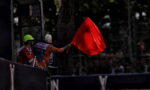 Race marshal waves a red flag to stop the race from the trackside barrier.