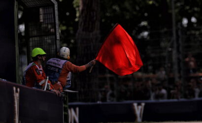 Race marshal waves a red flag to stop the race from the trackside barrier.