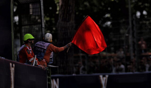 Race marshal waves a red flag to stop the race from the trackside barrier.