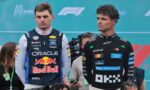 Two Formula 1 drivers stand side by side at a motorsport event, the left in an Oracle Red Bull racing suit and the right in a McLaren suit with sponsor logos, against a Miami F1 backdrop.
