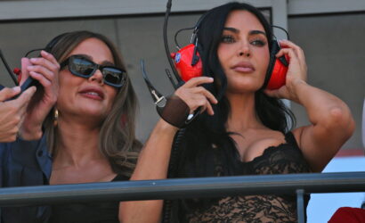 Two women in a VIP area wearing large headsets; one with sunglasses and a black lace top, the other adjusting her headset.