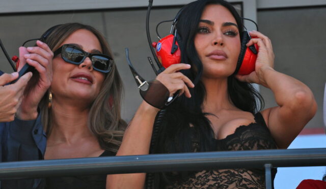 Two women in a VIP area wearing large headsets; one with sunglasses and a black lace top, the other adjusting her headset.