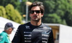 Man wearing a dark sponsor-logo shirt and sunglasses outdoors, looking to the side.