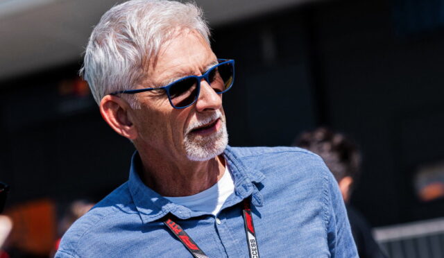 Older man with gray hair and beard, blue sunglasses, and a blue shirt, outdoors with a lanyard around his neck.