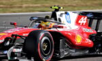 Red Formula 1 race car on a track with driver in yellow helmet, number 44 and Shell logo visible on the side