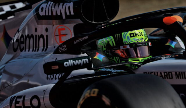 Close-up of a race car cockpit with a neon-green helmeted driver and sponsor logos on the body (informative)