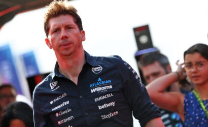 Man in a navy Williams F1 team shirt at an outdoor event, crowd in background.