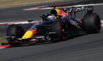 Red Bull Racing Formula 1 car on a race track, blue-black livery with yellow nose and large rear wing, cornering.