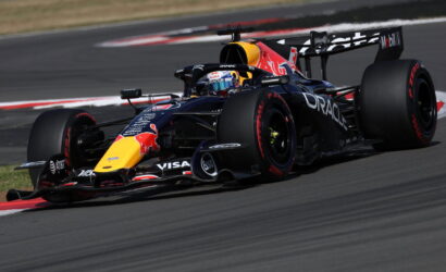 Red Bull Racing Formula 1 car on a race track, blue-black livery with yellow nose and large rear wing, cornering.