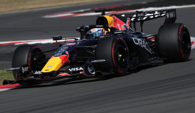 Red Bull Racing Formula 1 car on a race track, blue-black livery with yellow nose and large rear wing, cornering.