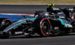 Mercedes-AMG F1 race car on track, front-left wheel in red, sponsor logos visible (Petronas, Microsoft) and teal accents on black livery.
