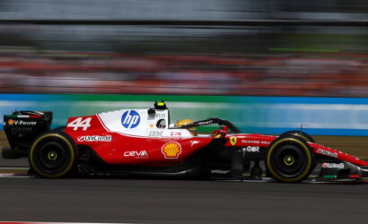 Red Formula 1 car with number 44 speeding on track, sponsor logos visible, motion blur emphasizes high speed.
