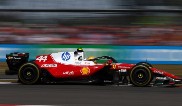 Red Formula 1 car with number 44 speeding on track, sponsor logos visible, motion blur emphasizes high speed.