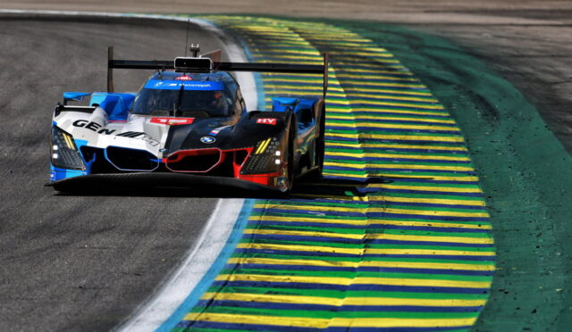 BMW race car taking a tight left-hander on a track, blue and yellow striped curbs visible on the inside.