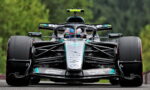 Mercedes‑AMG Petronas Formula One car, front view, racing on a track with green backdrop behind it