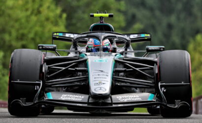 Mercedes‑AMG Petronas Formula One car, front view, racing on a track with green backdrop behind it