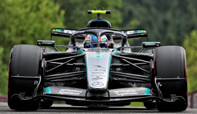 Mercedes‑AMG Petronas Formula One car, front view, racing on a track with green backdrop behind it