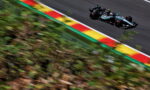 Mercedes Formula 1 car speeding along a race track with motion blur on the foreground greenery and red-yellow-green curbs