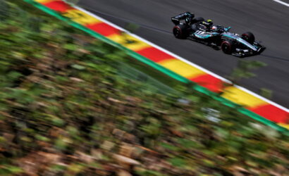 Mercedes Formula 1 car speeding along a race track with motion blur on the foreground greenery and red-yellow-green curbs
