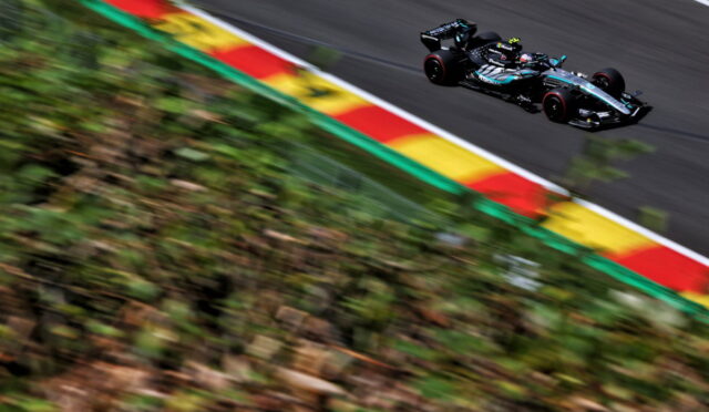 Mercedes Formula 1 car speeding along a race track with motion blur on the foreground greenery and red-yellow-green curbs