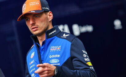 Formula 1 driver in Oracle Red Bull Racing gear with orange cap, looking to the left.