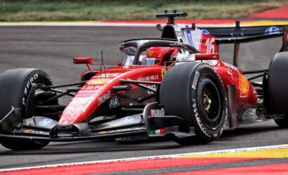 Red Ferrari Formula 1 car on a race track, close-up view showing sponsor logos and number 16 on the sidepod.