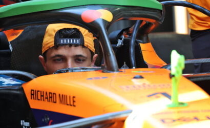 Driver wearing an orange cap sits in an orange race car cockpit labeled Richard Mille.