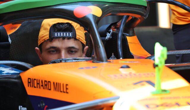 Driver wearing an orange cap sits in an orange race car cockpit labeled Richard Mille.