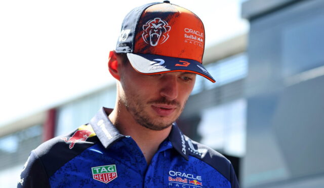 Portrait of a man in an Oracle Red Bull Racing cap and blue team polo, looking down with sponsor logos visible on clothing.