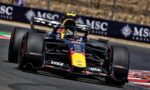Red Bull Racing Formula 1 car powering through a sharp turn on a race track, with sponsor logos visible.