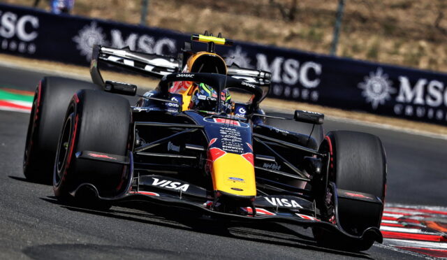 Red Bull Racing Formula 1 car powering through a sharp turn on a race track, with sponsor logos visible.