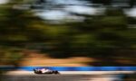 Formula 1 car speeding along a race track with motion blur in the background to convey high speed and motion.
