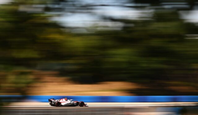 Formula 1 car speeding along a race track with motion blur in the background to convey high speed and motion.