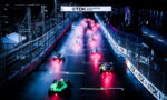 Racing cars at a night-start on a wet track, red exhaust glow trailing behind them under a TDK banner.