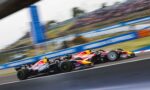 Two Red Bull Racing Formula 1 cars race side by side on a track with a blurred grandstand backdrop due to motion blur.