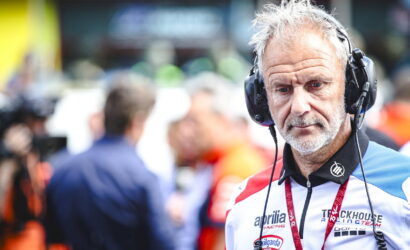 Motor race team member wearing a headset and branded racing suit, focused in the pit area.
