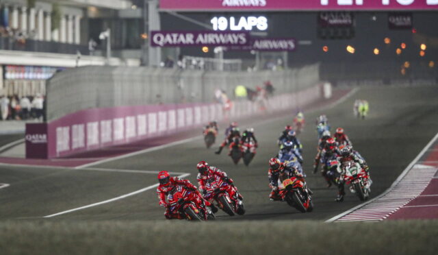 Motorcycle race on a curving track with riders leaning into a turn; Qatar Airways banners overhead.