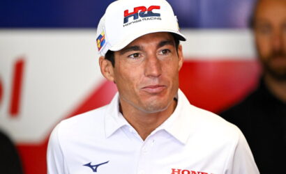 Man wearing a white Honda Racing cap and polo shirt at a press event.