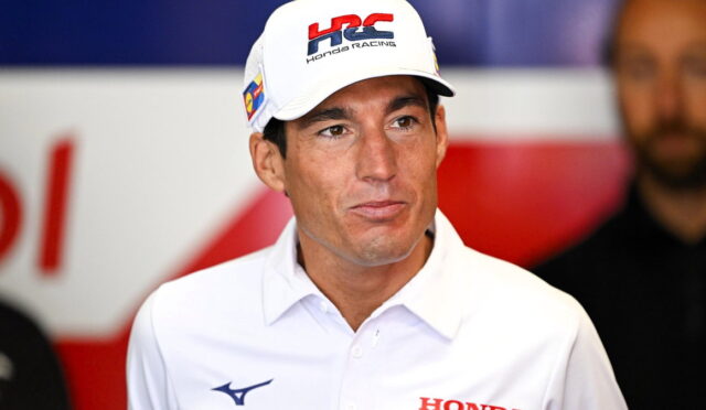 Man wearing a white Honda Racing cap and polo shirt at a press event.