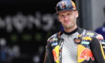 Moto racer in a KTM/Red Bull racing suit, looking at the camera outdoors.