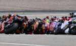 Pack of motorcycle racers leaning into a tight turn on a race track.