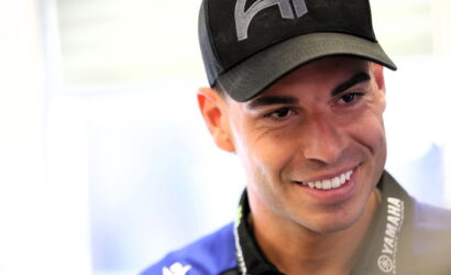 Smiling man wearing a black cap and Yamaha lanyard, close-up portrait.