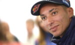Close-up of a young man wearing a navy cap with Red Bull and sponsor logos, looking at the camera.