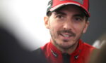 Close-up of a man in a red racing cap and jacket smiling at the camera.